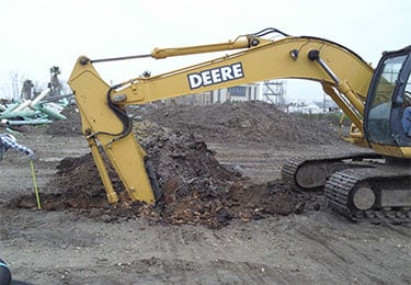 Crane putting scoop into dirt